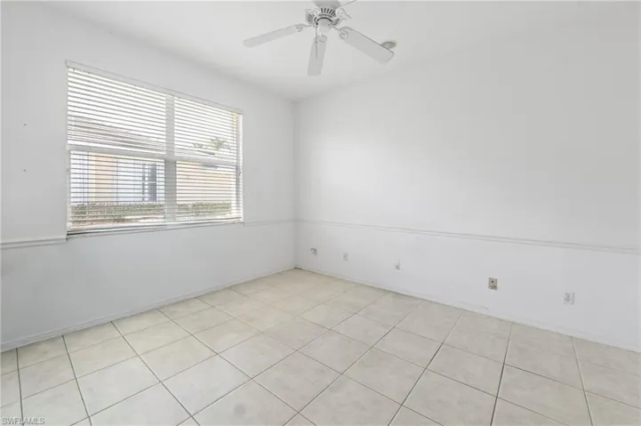 Room featuring light-toned square tile flooring, a window with horizontal blinds, and a white ceiling fan