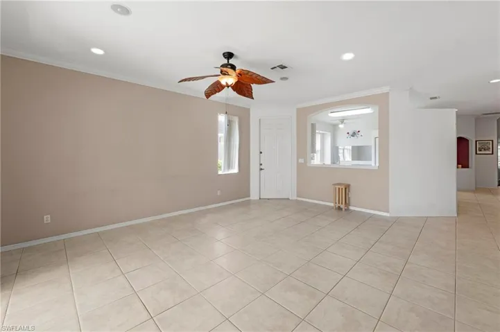 Spacious living area featuring neutral tile flooring, recessed lighting, and a ceiling fan