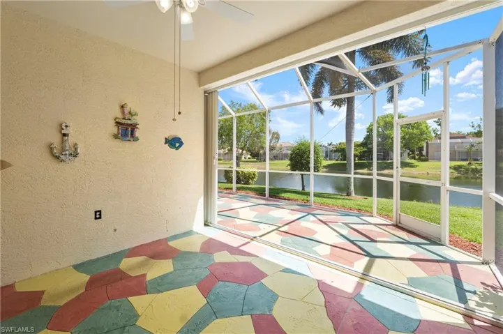 Screened patio featuring a colorful geometric patterned floor, a ceiling fan with light fixture, and expansive water frontage