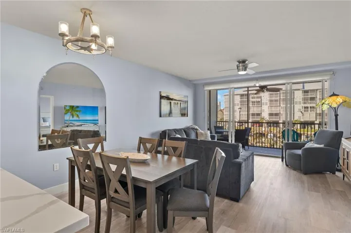 Dining space featuring light wood finished floors, arched walkways, and ceiling fan with notable chandelier