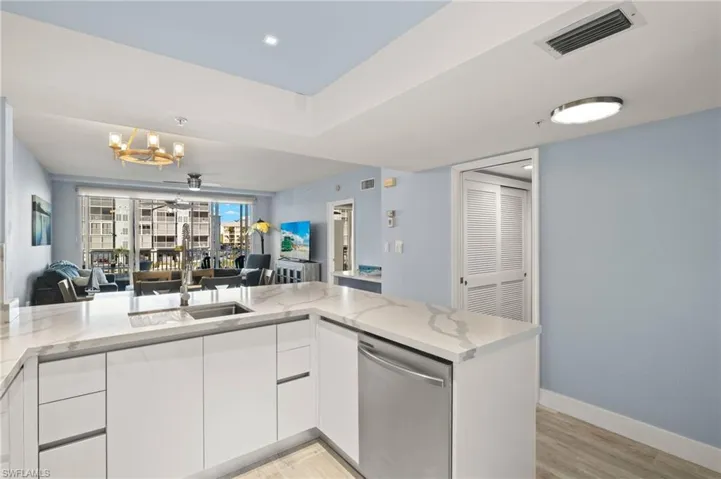 Kitchen featuring open floor plan, dishwasher, light wood-style flooring, light stone countertops, and visible vents