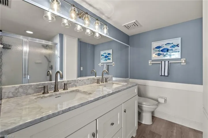 Full bathroom featuring toilet, a sink, visible vents, and a stall shower