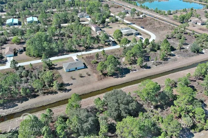 Aerial overview of property's location featuring a nearby body of water and a tree filled landscape