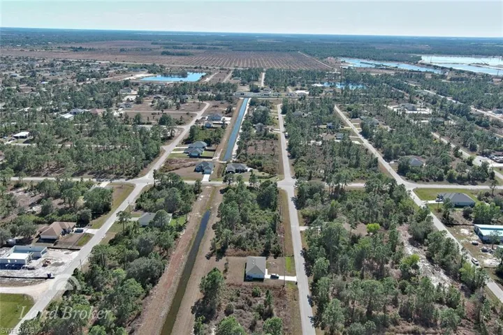Aerial view of property and surrounding area featuring rows of crops, a nearby body of water, and rural landscape