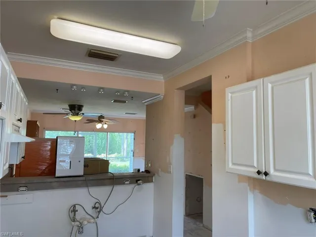 Kitchen with ornamental molding, white cabinetry, tile countertops, and ceiling fan. View to Dining Area