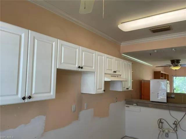 Kitchen featuring ornamental molding, white cabinetry, and ceiling fan