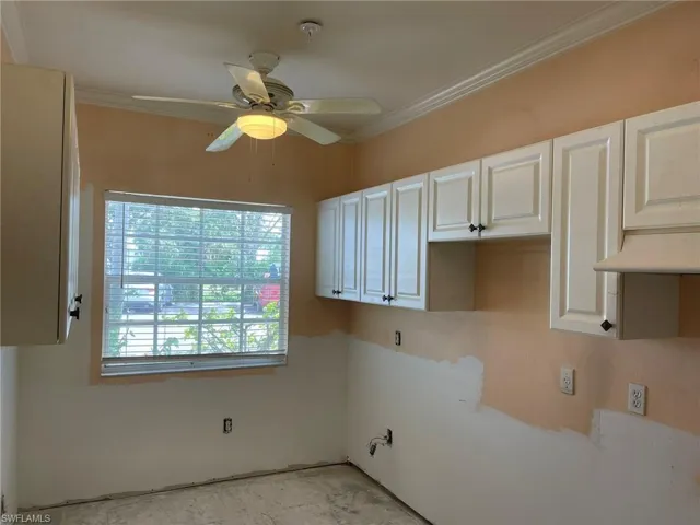 Kitchen featuring ceiling fan, white cabinetry, and crown molding