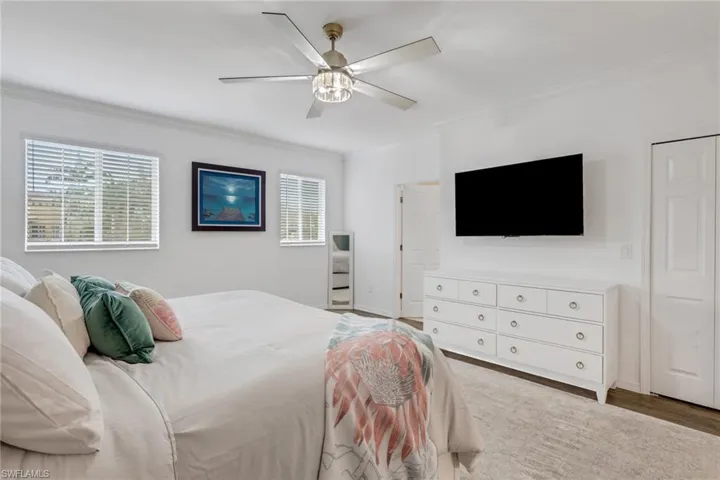 Bedroom with ornamental molding, a ceiling fan, and wood finished floors