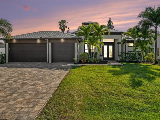 View of front of home featuring french doors, decorative driveway, a standing seam roof, a garage, and a front yard
