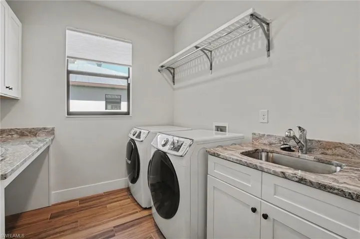 Laundry room featuring cabinet space, dark wood-type flooring, and washer and clothes dryer