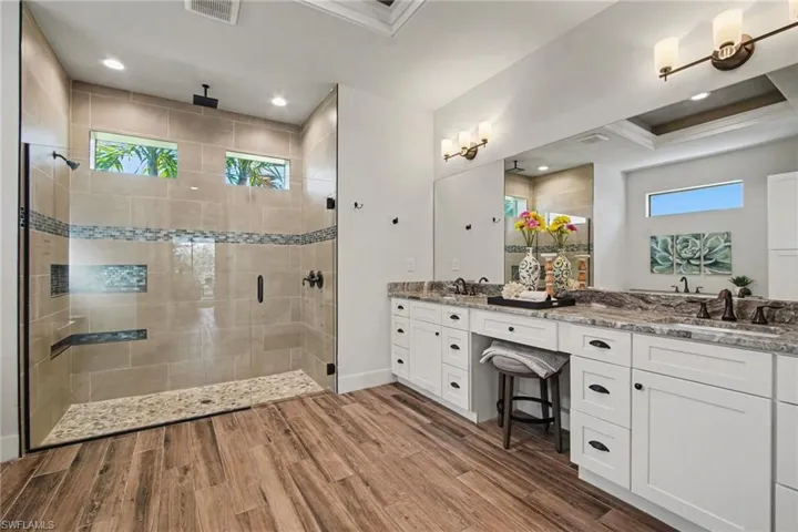 Bathroom with a shower stall, double vanity, plenty of natural light, dark wood-style floors, and recessed lighting