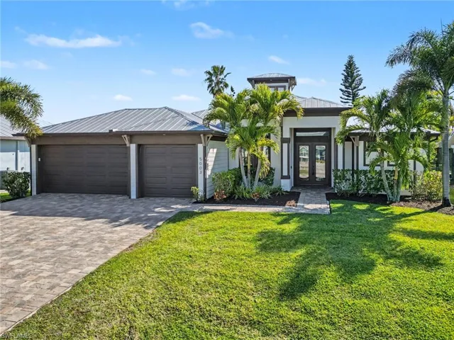 View of front of property with french doors, driveway, a front yard, and a garage