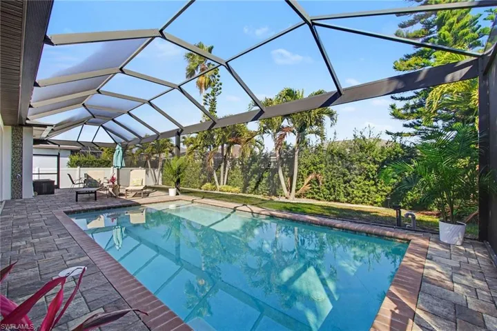 Swimming pool with a sunroom, glass enclosure, and a patio area