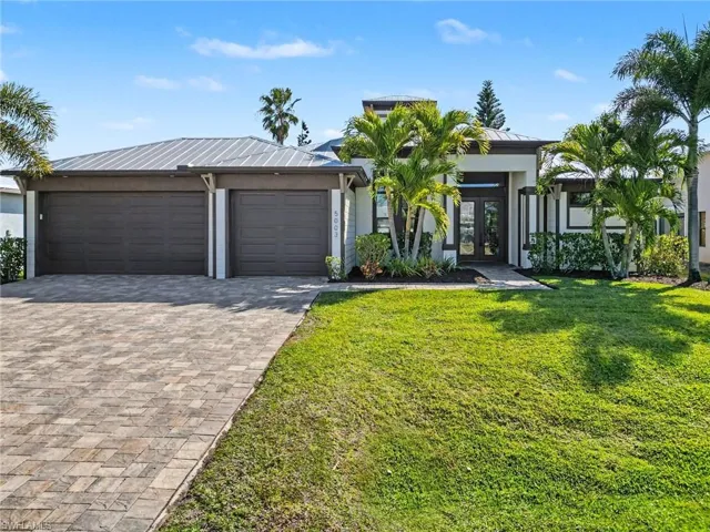 View of front of home featuring french doors, decorative driveway, an attached garage, a front lawn, and a standing seam roof