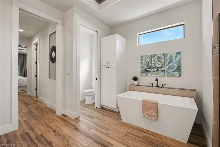 Full bath featuring light wood-style flooring, a soaking tub, and connected bathroom