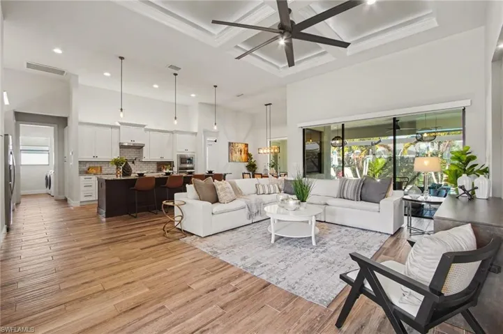 Living area with coffered ceiling, ceiling fan, light wood-style flooring, recessed lighting, and washer / dryer