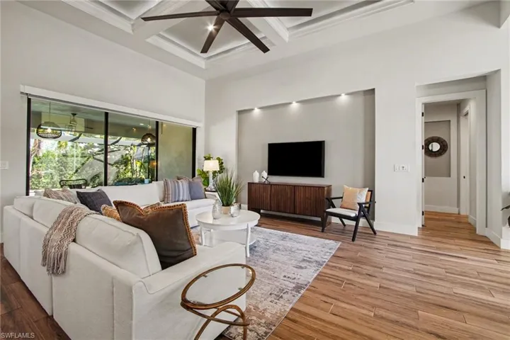Living room featuring a ceiling fan, coffered ceiling, and light wood finished floors
