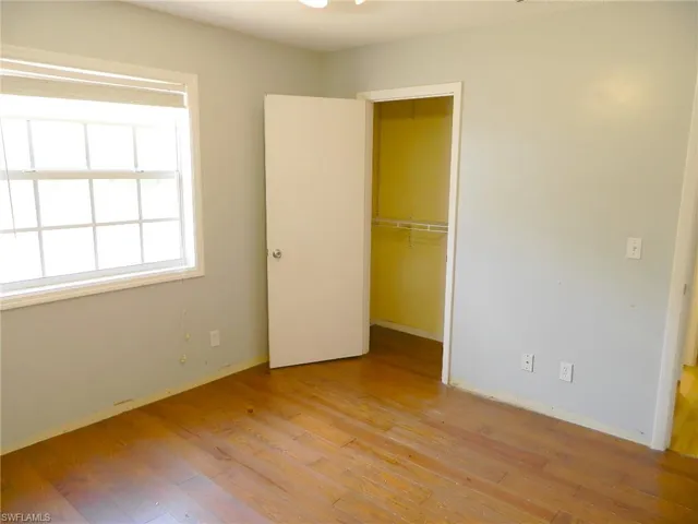 Unfurnished bedroom with light wood finished floors, a closet, and baseboards