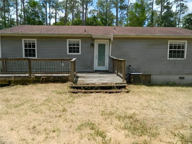 Back of house with a wooden deck, crawl space, a yard, and a shingled roof