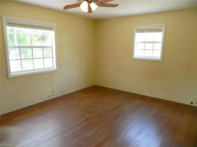 Empty room with healthy amount of natural light, a ceiling fan, and wood finished floors