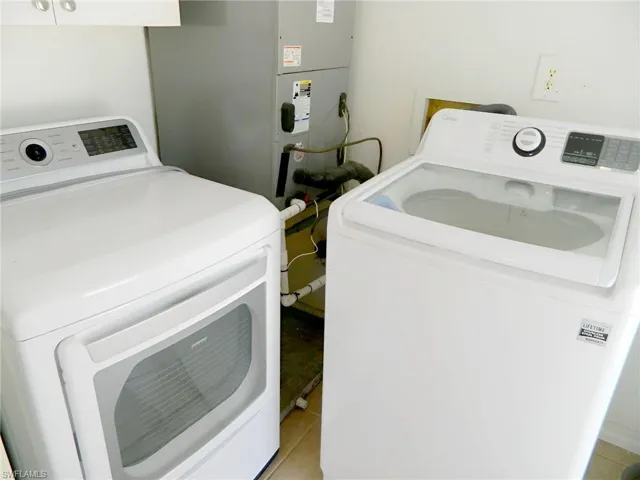 Clothes washing area featuring washing machine and dryer and light tile patterned floors