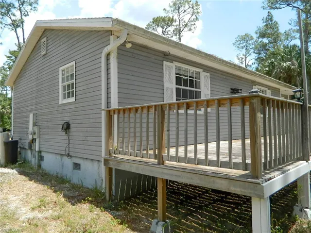 Rear view of house with a wooden deck and crawl space