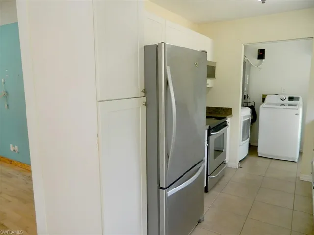 Kitchen featuring washer / dryer, appliances with stainless steel finishes, white cabinetry, and light tile patterned floors
