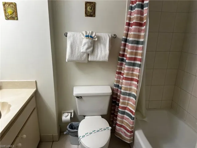 Full bathroom with toilet, vanity, and shower / bathtub combination with curtain