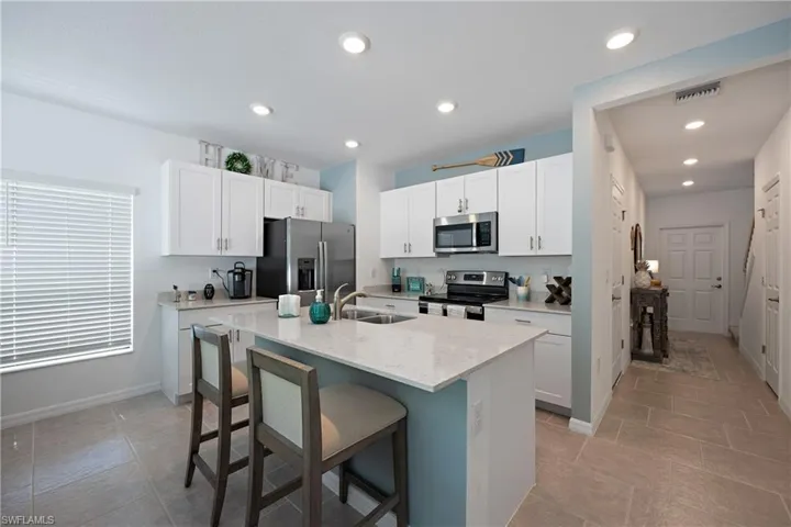 Kitchen with an island with sink, stainless steel appliances, and white cabinets