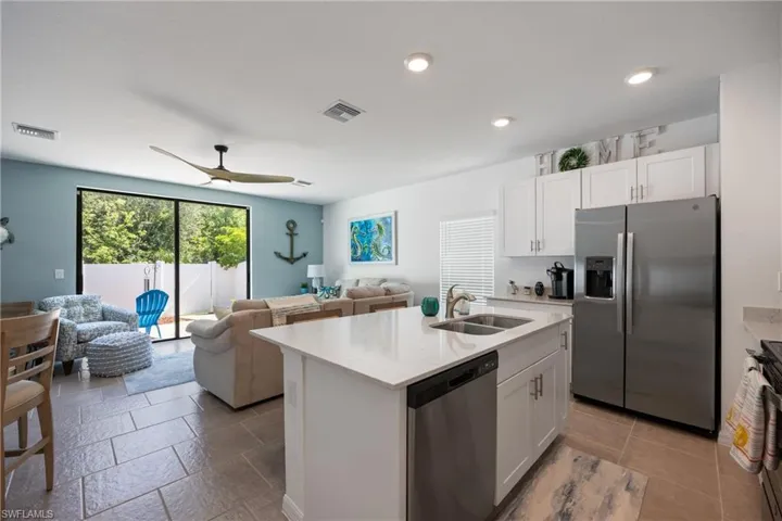 Kitchen featuring appliances with stainless steel finishes, sink, white cabinets, and an island with sink
