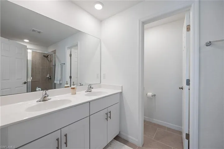 Bathroom featuring dual vanity, an enclosed shower, and tile floors