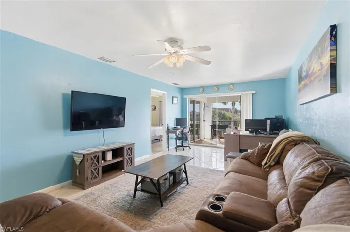 Living area with tile patterned floors and a ceiling fan