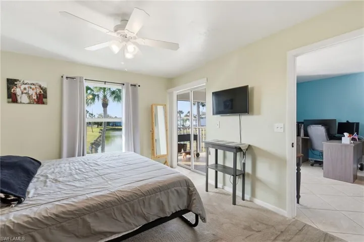 Bedroom featuring access to exterior, ceiling fan, light colored carpet, light tile patterned floors, and an office area