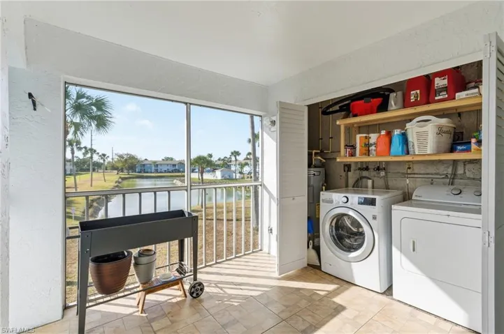Laundry area featuring a textured wall, separate washer and dryer, and a water view