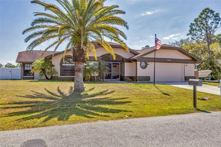View of front of home featuring stucco siding, an attached garage, driveway, and a front lawn