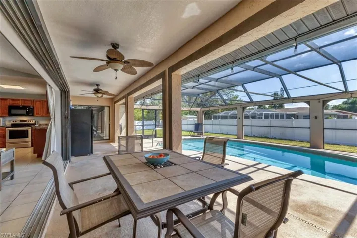 View of patio / terrace featuring glass enclosure, a fenced in pool, ceiling fan, and fence