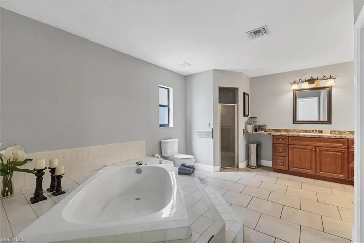 Full bath with a garden tub, toilet, a shower stall, tile patterned flooring, and vanity