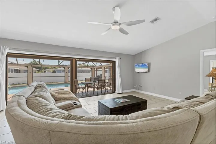 Living room with light tile patterned floors, baseboards, visible vents, lofted ceiling, and ceiling fan