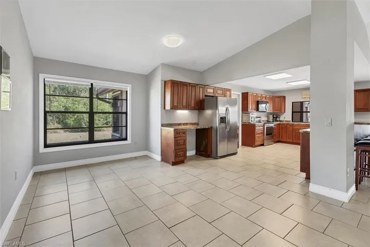 Kitchen featuring appliances with stainless steel finishes, baseboards, and vaulted ceiling