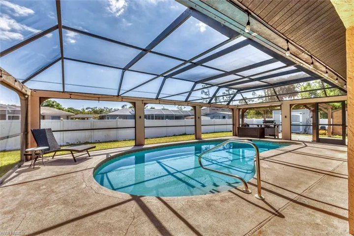 View of pool with glass enclosure, a patio area, and a fenced backyard
