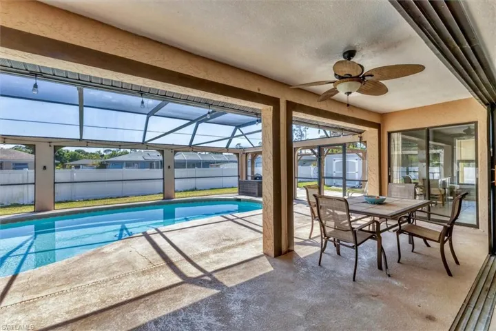 View of swimming pool with a patio, fence, a lanai, and a shed