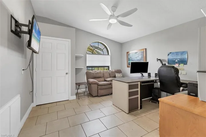 Office area featuring light tile patterned floors, baseboards, lofted ceiling, and ceiling fan