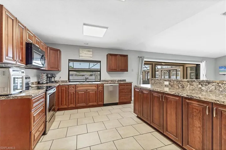 Kitchen with a toaster, light stone countertops, stainless steel appliances, and a sink