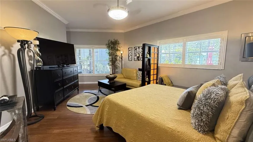 Bedroom featuring wood finished floors and crown molding