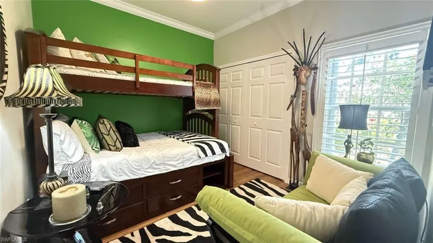 Bedroom featuring a closet, ornamental molding, and wood finished floors
