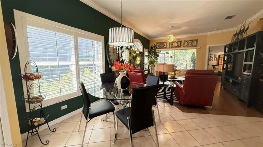 Dining space with crown molding, tile patterned flooring, and ceiling fan