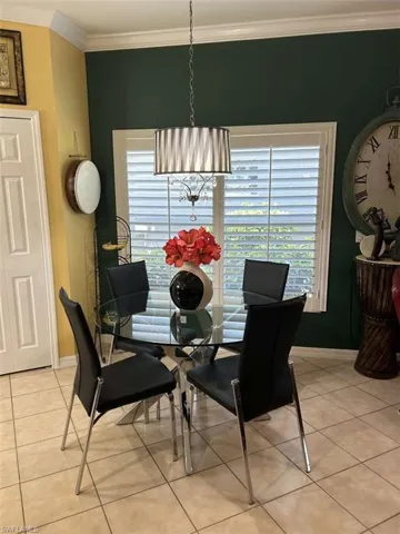 Dining space with light tile patterned flooring, a chandelier, ornamental molding, and healthy amount of natural light