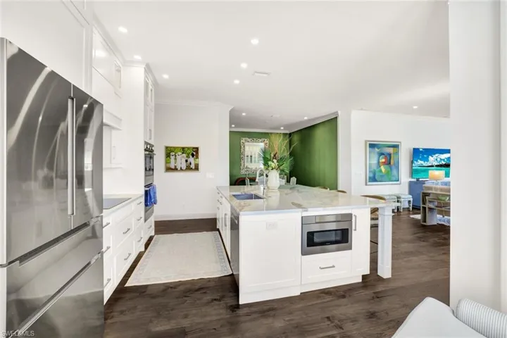 Kitchen with sink, appliances with stainless steel finishes, dark hardwood / wood-style floors, white cabinets, and a center island with sink