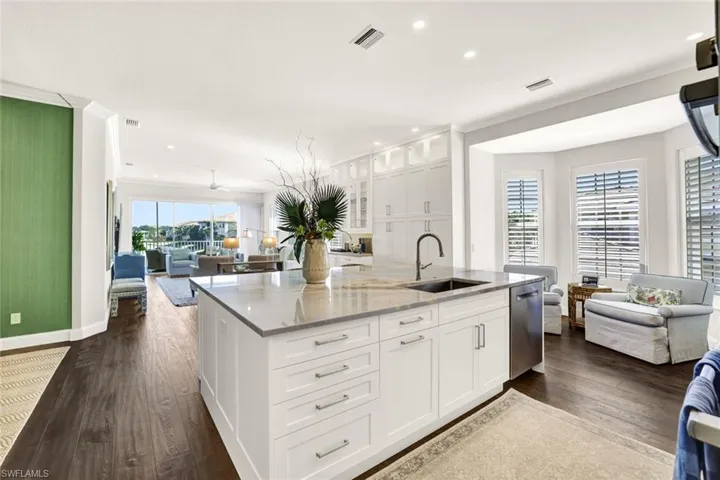 Kitchen with sink, white cabinetry, a center island with sink, dishwasher, and light stone countertops