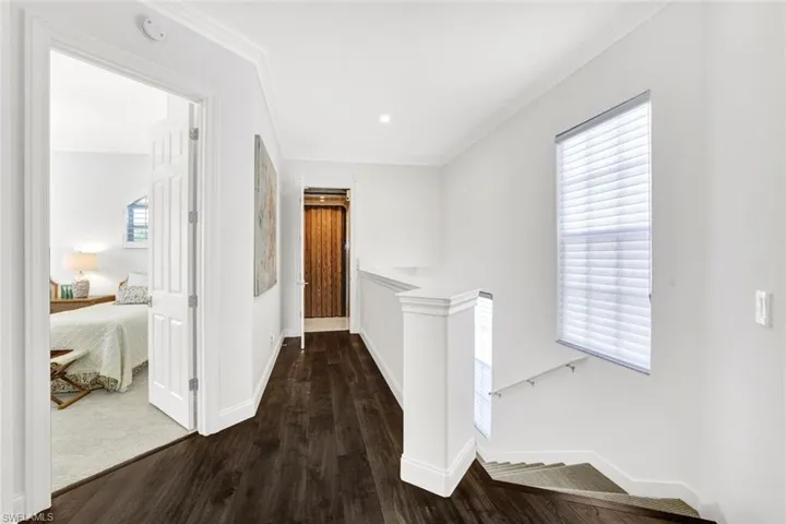 Hall with ornamental molding and dark hardwood / wood-style floors